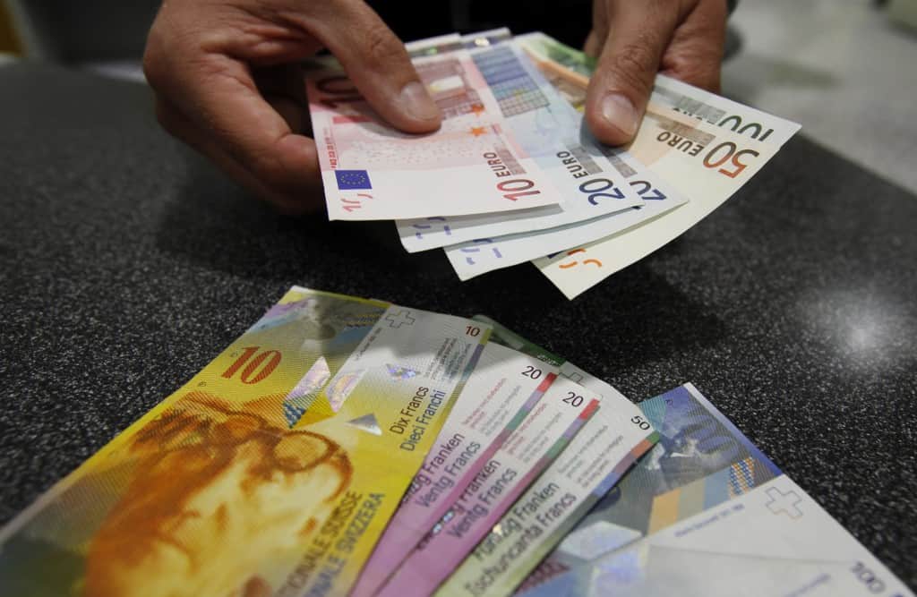 A illustration picture shows a Swiss Post clerk as he exchanges Swiss francs into Euros at a counter in a Swiss Post office in Bern August 8, 2011. A shock cut in interest rates to near zero last week failed to halt gains in the Swiss franc and the Swiss National Bank now has to decide on what further steps it could take and whether to embark on costly intervention to ease the currency's appeal. REUTERS/Pascal Lauener (SWITZERLAND - Tags: POLITICS BUSINESS)